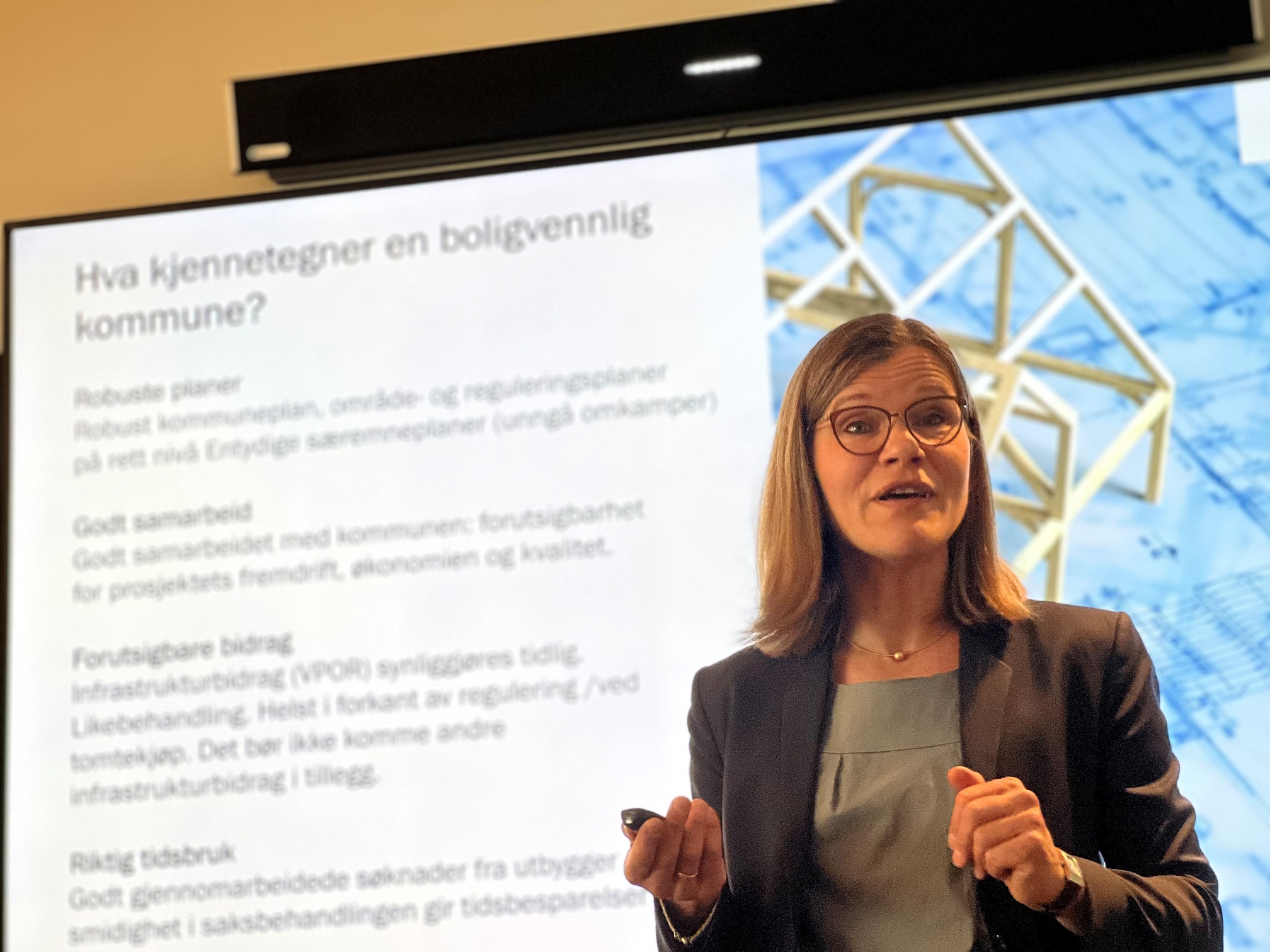 Kvinne holder foredrag foran skjerm