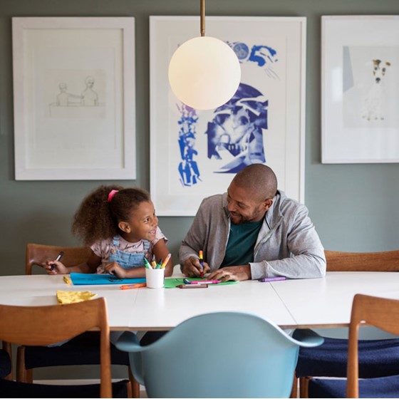 En far og datter som sitter ved et spisebord og tegner.