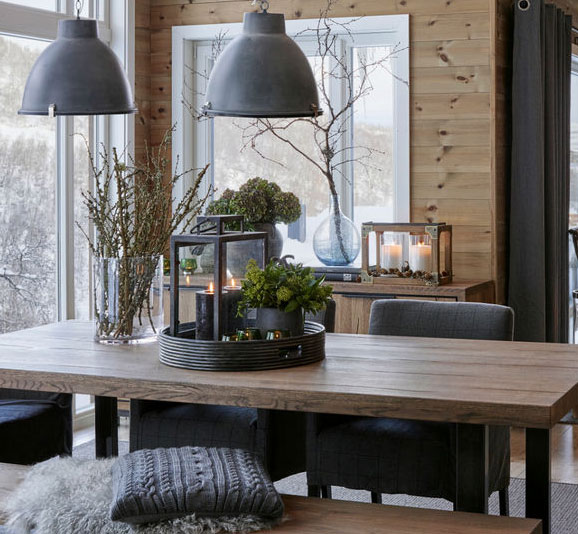 Spisestue fra Bohus Lillehammer med mye treverk og grå lamper, saueskinn og puter.