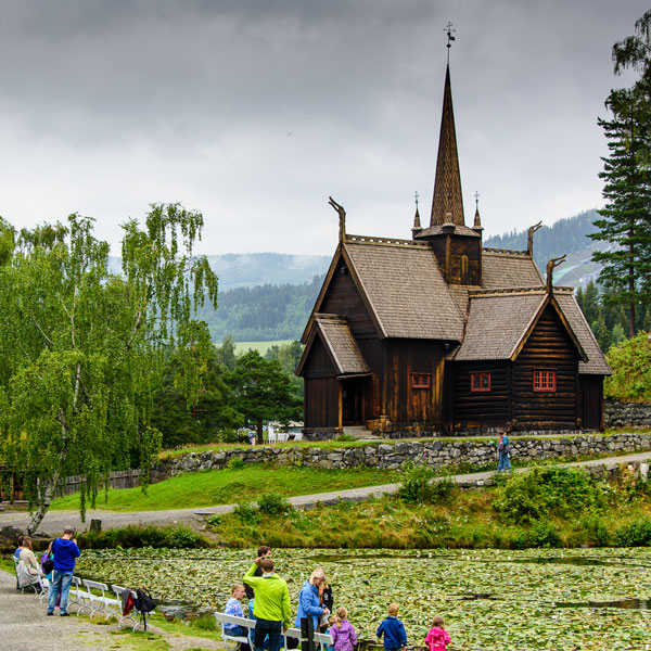Stavkirke i Lillehammer med fjell i bakgrunn.