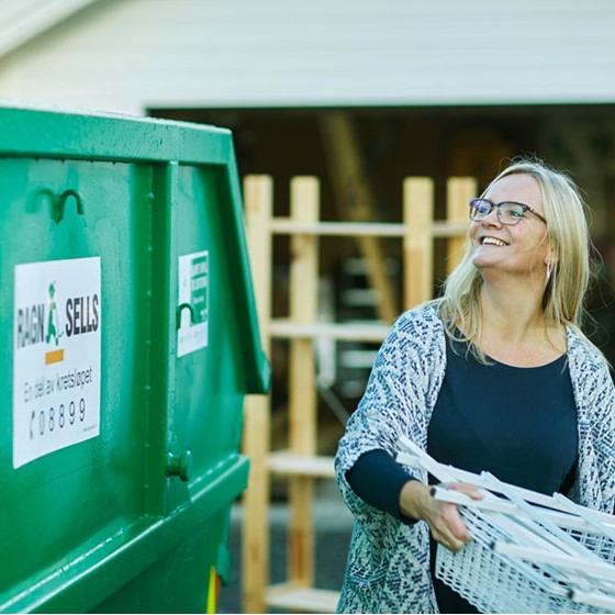 Kvinner som kaster avfall i en Ragn-Sells søppelcontainer.