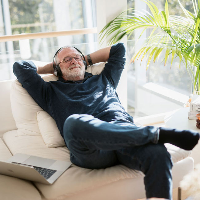 En Usbl styremedlem som lener tilbake på sofaen og smiler. Han bruker hodetelefoner og koser seg. 